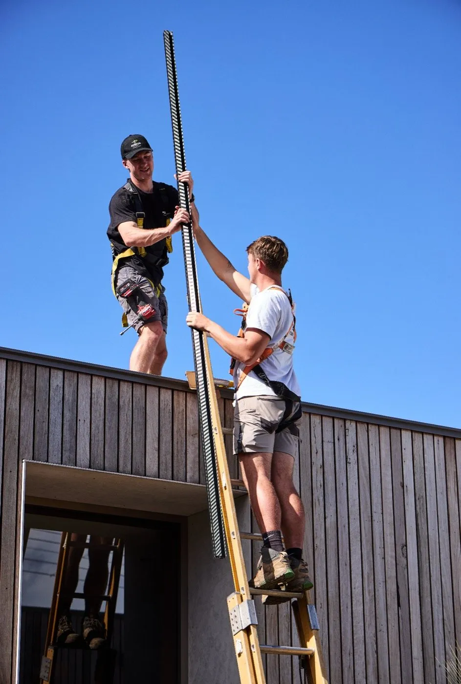 An installer passing mounting rail up a ladder