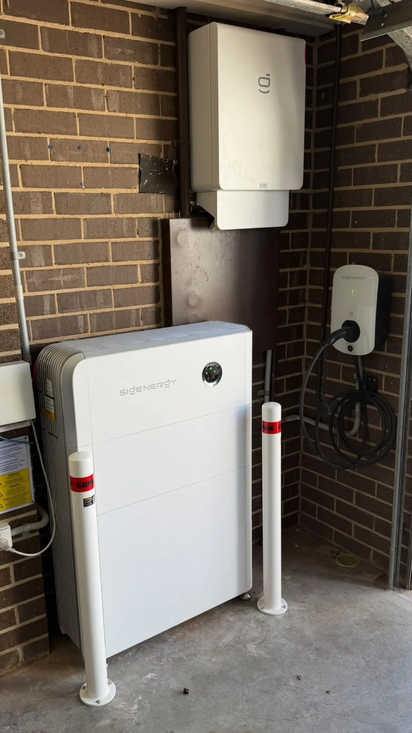 A Sigenergy SigenStor battery and inverter installed in a garage, beside a Sigenergy EV charger